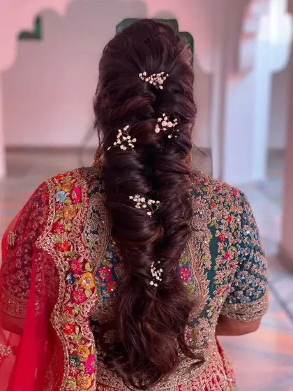 A volumized soft braid for her big day. This romantic and intricate style is perfect for a bride, with delicate baby's breath tucked in for a touch of softness.