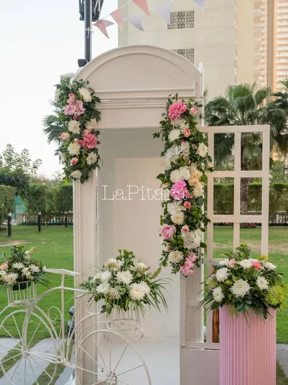 A charming photo booth designed for a bow-themed birthday party. We used a classic white telephone booth and adorned it with beautiful garlands of pink and white flowers for a sweet, whimsical touch.