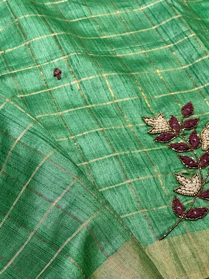 The delicate embroidery on the green Tussar silk saree. The combination of beadwork and threadwork creates a beautiful floral motif.