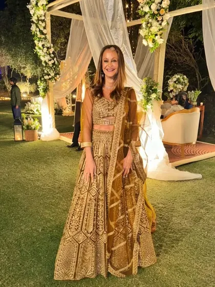 A client looking elegant at an outdoor wedding in our golden-brown lehenga. The outfit is perfect for a sophisticated evening event.