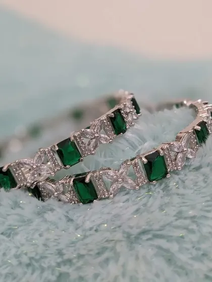 A pair of elegant American Diamond bangles with emerald-green stones. These are complimentary when you rent a complete set.