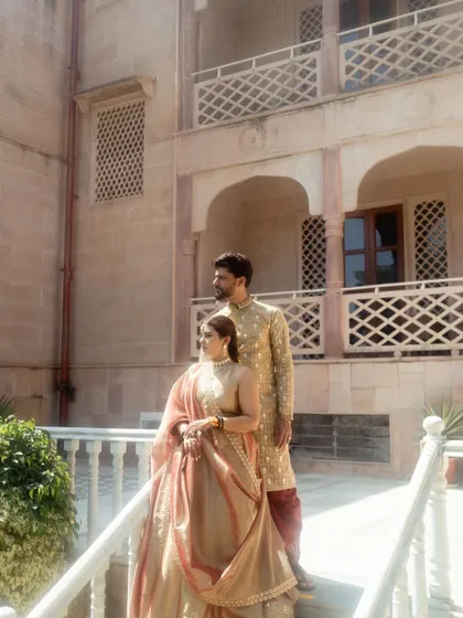 A classic portrait of the couple on a balcony at their palace wedding venue. Their regal poses and coordinated outfits make for a timeless and elegant photograph.