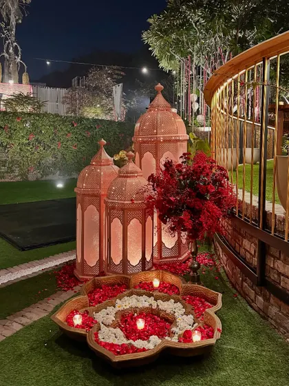 Large copper-toned Moroccan lanterns paired with a floral rangoli, creating a grand and welcoming decor piece.