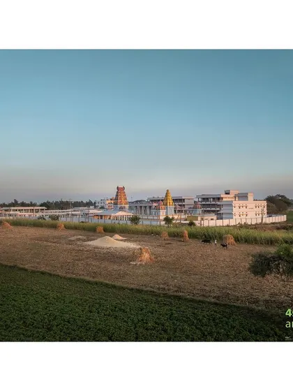 The temple complex viewed from the surrounding agricultural fields, showing how the design is situated within its rural context while creating a distinct spiritual oasis.