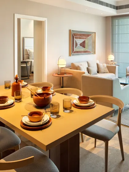 An open-plan dining area at the Elevate project. The simple wooden table and chairs are complemented by earthy tableware, creating a warm and inviting setting for family meals.