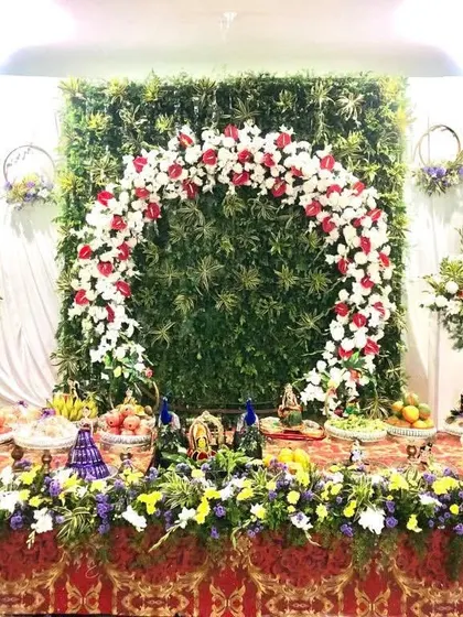 A fresh and vibrant display with a backdrop of green leaves and a floral arch. The long table is filled with my decorated gift platters, creating a stunning visual for a daytime event.