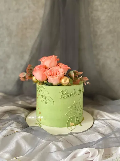 Another angle of the sage green bride-to-be cake, showing off the beautiful contrast between the soft green frosting and the fresh pink roses.