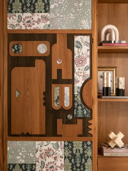 A close-up of a custom cabinet door, where different fabrics are inlaid within a wooden frame, creating a rich, patchwork effect.