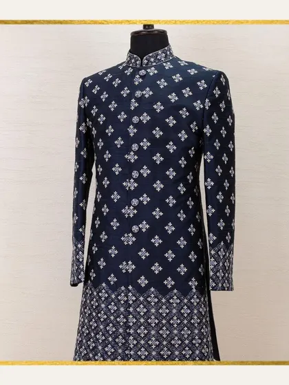 A mannequin showcases a navy sherwani with a classic, repeating geometric pattern. This image is a testament to our commitment to timeless elegance and the epitome of Indian menswear.