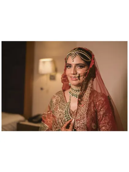 A classic bridal portrait. The bride looks directly at the camera with a gentle smile, her intricate jewelry and stunning makeup perfectly captured.
