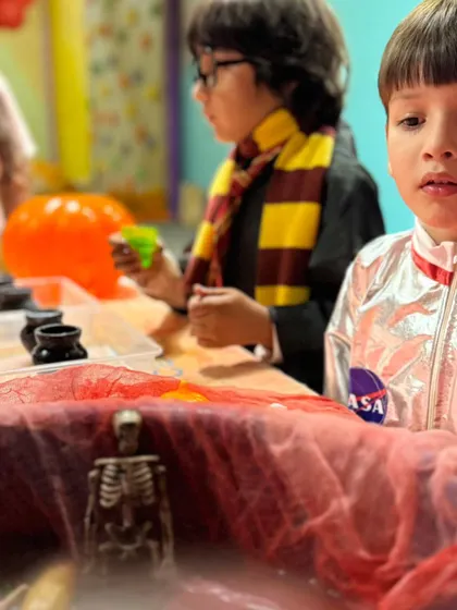 An astronaut and a wizard stand side by side, completely hooked on the spooky science experiment in front of them.