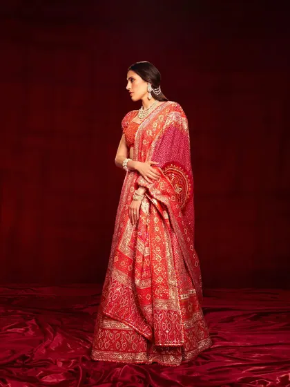 A classic red bandhani lehenga by Abu Jani Sandeep Khosla. This is a timeless look, perfect for a traditional ceremony, exuding grace and heritage.