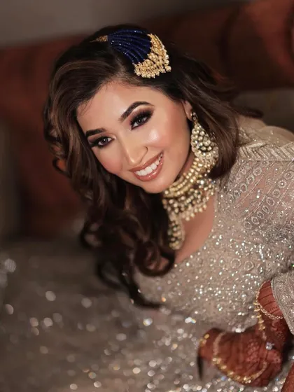 A happy Sangeet bride. Her look features a bold eye, glowing skin, and a beautiful smile.