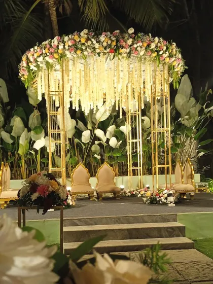 Another angle of this stunning modern mandap. The clean lines of the golden frame contrast beautifully with the lush tropical foliage in the background, perfect for an evening ceremony.