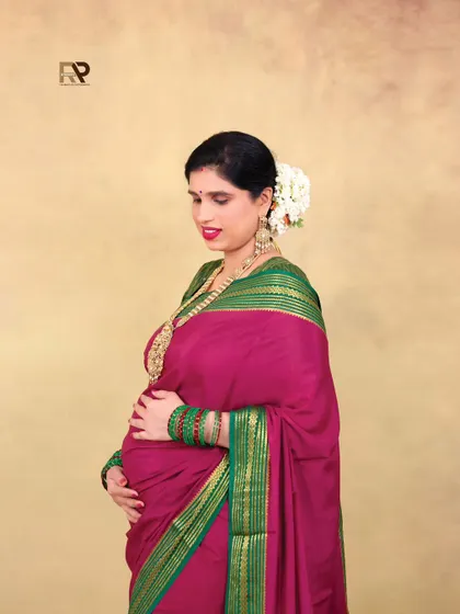 A simple and elegant solo portrait. The focus is on the mom-to-be's gentle expression as she cradles her bump, her traditional jewelry and attire adding to the grace.