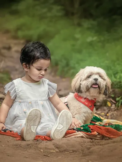 There is a special magic when a child and their furry friend share a quiet moment. This outdoor portrait captures the gentle, unspoken bond between a little girl and her dog on a rustic forest path.