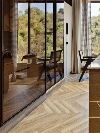 The finished walk-in closet, where our design comes to life. The herringbone wooden flooring and custom cabinetry with integrated lighting create a luxurious and highly functional space that overlooks the natural landscape.