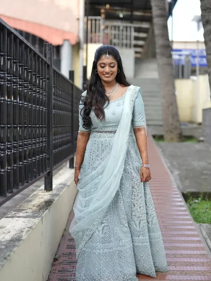A full-length view of a client's beautiful pastel blue lehenga for an evening event. The soft waves and subtle makeup complete the elegant look.