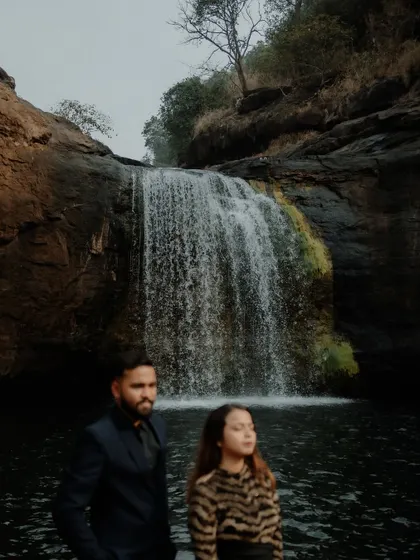 A dramatic couple portrait with a waterfall in the background. The power of nature adds a grand scale to pre-wedding photography.