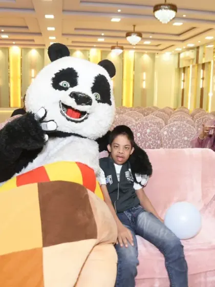A young guest sits with the panda mascot on the couch.