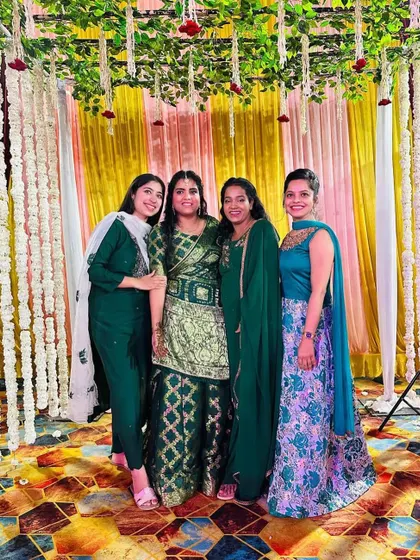 The bride and her bridesmaids enjoying the celebration. The backdrop of white floral strings against yellow and pink drapes provides a soft yet festive setting for group photos.