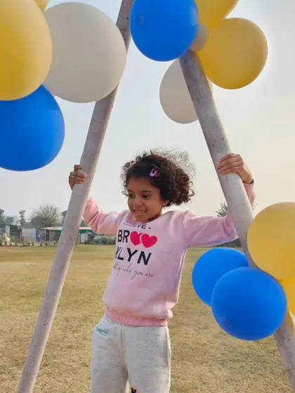 Pure, simple fun. A young girl plays on a swing set decorated with balloons during a party.
