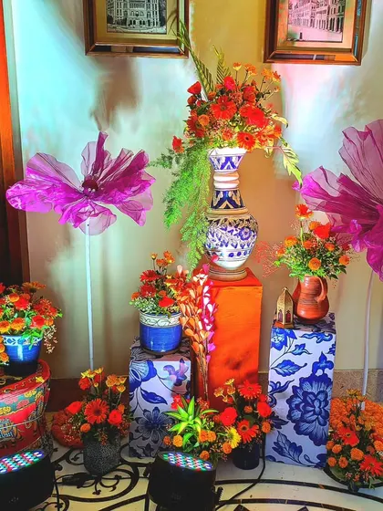 This corner arrangement combines the vibrant colors of the Haldi theme with artistic flair. I used patterned pedestals, oversized paper flowers, and a mix of traditional pottery and florals.