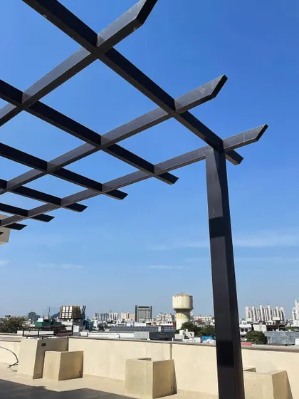 A close-up of the metal rafter pergola structure. The clean lines and durable construction provide a modern framework that can be customized with climbers, shades, or lighting.