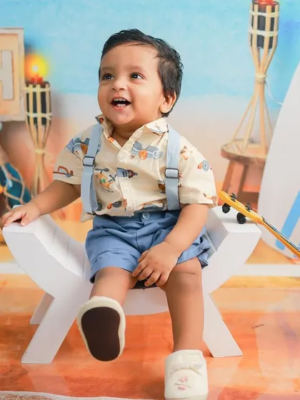 A happy little boy enjoying his beach-themed photoshoot. His joyful expression and the colorful, detailed setup create a picture-perfect memory.