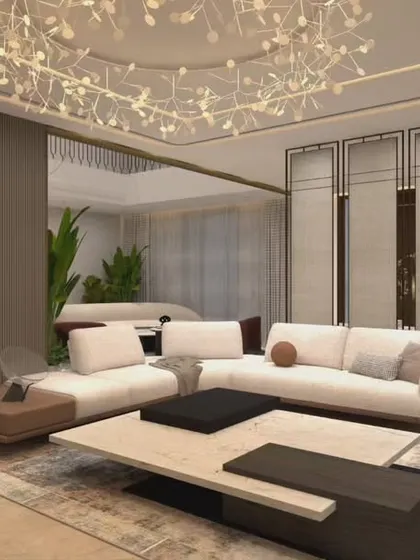 A sophisticated living room where lighting plays a key role. The intricate ceiling light fixture acts as a piece of art, while the room divider adds a layer of privacy and architectural interest. The low-slung sofa keeps the feel modern and relaxed.