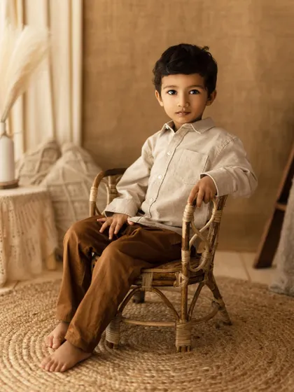 A poised and handsome portrait of a young boy in a rattan chair. This shot, from a lifestyle session, has the classic feel of a fine art portrait.