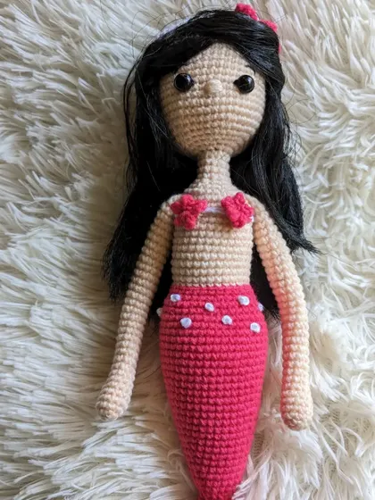 The full mermaid doll lying on a fluffy white surface.