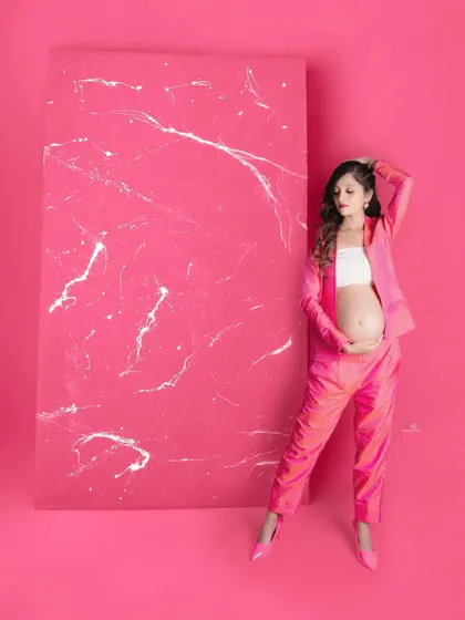 A full-body shot showcasing this amazing pink pantsuit. This is a great example of a modern, non-traditional maternity look that is full of personality.