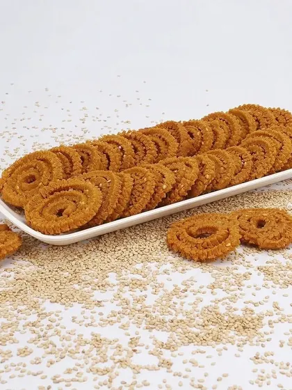 A clean, organized presentation of chakli snacks on a long platter, with sesame seeds scattered around to highlight a key ingredient.