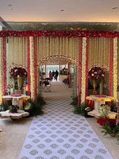 A breathtaking entrance for a traditional wedding ceremony, adorned with thousands of fragrant white mogra and deep red flowers. This grand floral archway sets a tone of reverence and opulence for the sacred event.