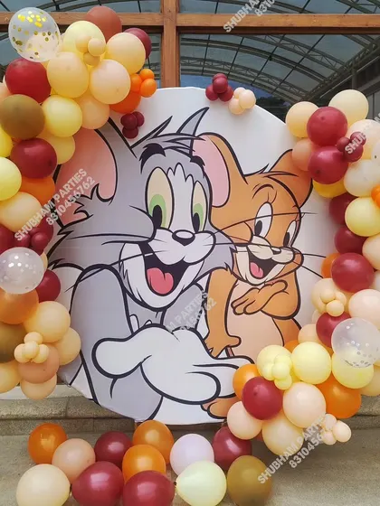 A fun Tom and Jerry themed circular backdrop surrounded by balloons in a neutral color palette.