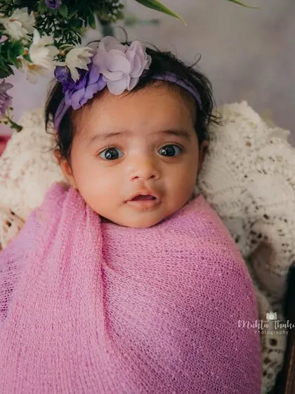 Wrapped up like a little flower bud. The purple tones and floral headband make this 3-month milestone photo so sweet and delicate.
