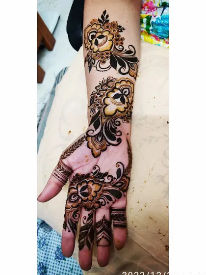 A graceful Arabic-style floral vine that sweeps across the hand and up the arm.