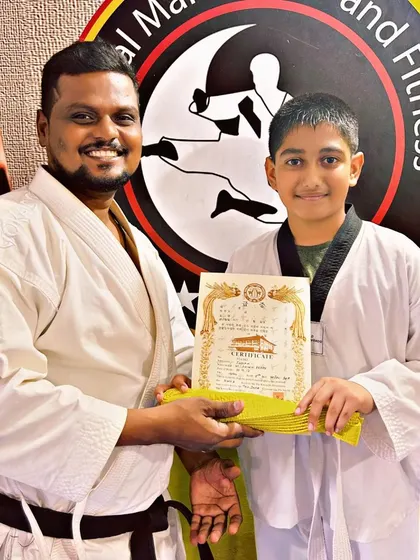 A young boy receives his yellow belt, a proud moment that boosts confidence and encourages further practice.