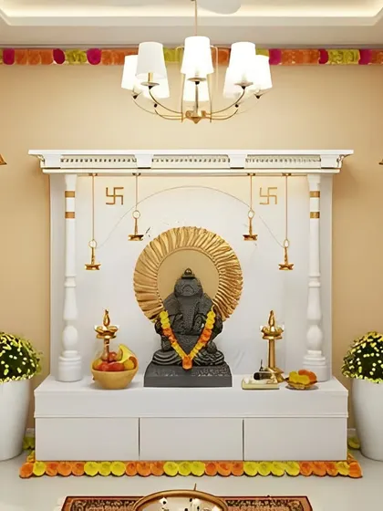 A freestanding white pooja mandap with a traditional structure, decorated for a ceremony. The unit includes a large platform for the main idol and three concealed storage cabinets below.