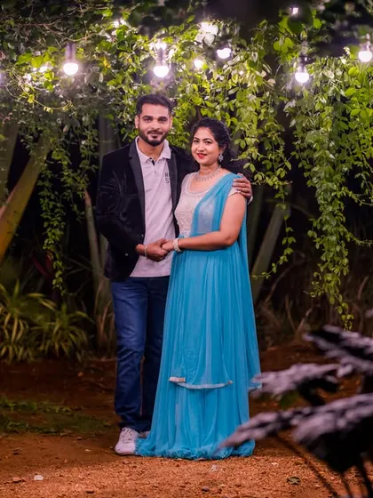 A full-length portrait of a couple under a canopy of hanging lights in our lush garden.