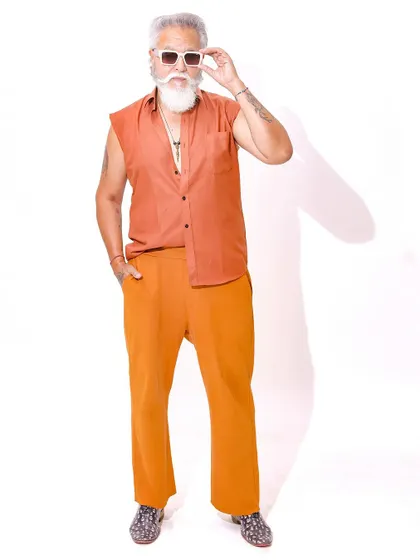 The model adjusts his sunglasses, adding a touch of cool and character to this bright and energetic fashion shot.