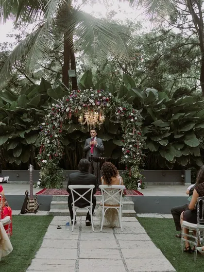 A wide shot of an outdoor Christian wedding ceremony, showing guests seated as the couple exchanges their vows in a beautiful garden setting.