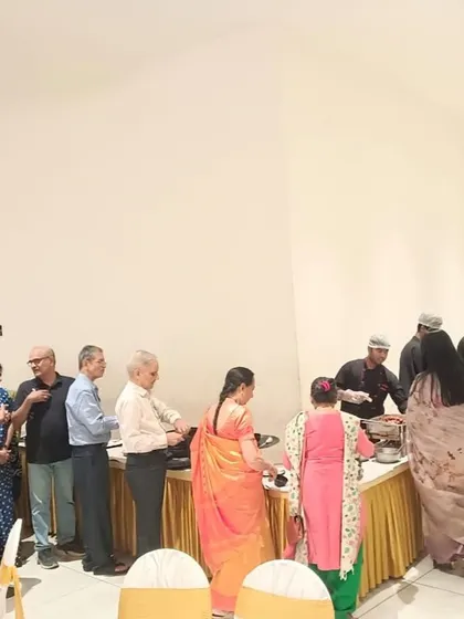 A candid photo of guests lining up for food at an anniversary party, showcasing a smooth and efficient buffet service.