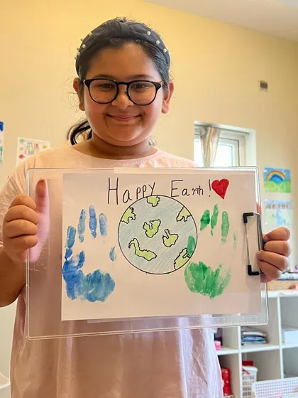 A happy artist gives a thumbs-up for her "Happy Earth" drawing. We love celebrating Earth Day and teaching kids to care for our planet through art.