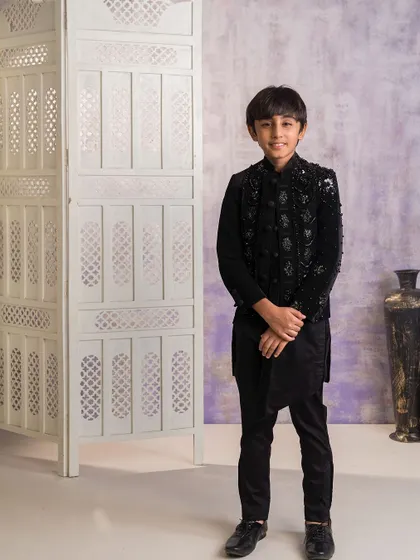 This is a sophisticated Indo-western outfit I created for an older boy. It features a heavily embellished black velvet jacket worn over an asymmetrical black kurta and trousers, ideal for a formal wedding reception.