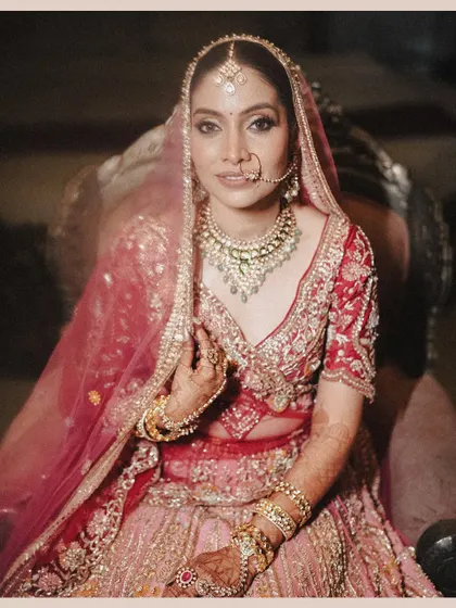 A classic bridal portrait, capturing the bride's gentle smile and the stunning details of her jewelry and pink lehenga.