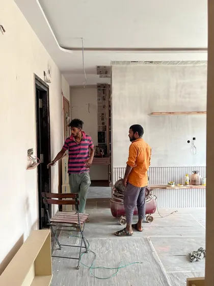 Our carpenters are the real masterpieces on site. Here, they're discussing the next steps in a room with newly installed fluted wall panels and a textured finish.