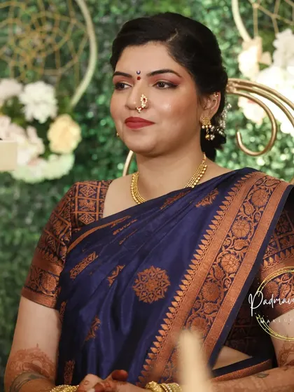 Another shot from the Varapuja, showing the bride in a candid moment. The makeup is designed to look natural and radiant in any lighting, enhancing her serene expression.