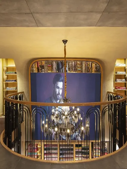 The mezzanine level at Ahujasons offers a dramatic overlook of the ground floor. This vantage point highlights the store's spatial choreography, with the custom railing and chandelier acting as key design elements that blend traditional and modern aesthetics.